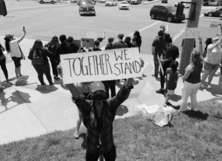 A diverse group of activists protesting peacefully with signs on a street corner.