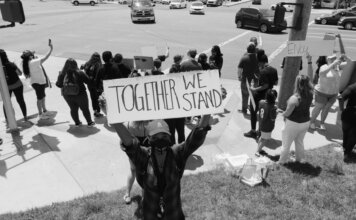 A diverse group of activists protesting peacefully with signs on a street corner.