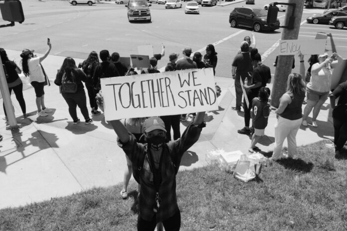 A diverse group of activists protesting peacefully with signs on a street corner.