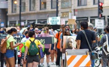 A diverse group of protesters gather peacefully in a city, advocating for justice reform.
