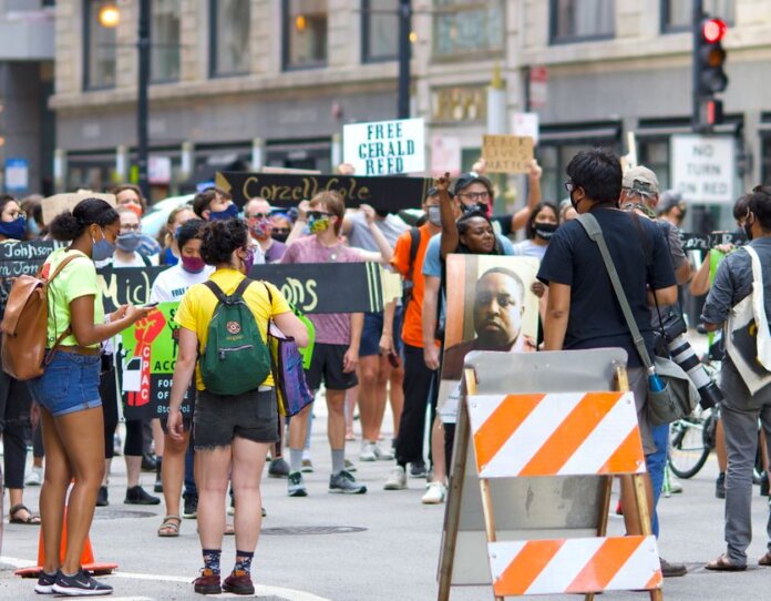 A diverse group of protesters gather peacefully in a city, advocating for justice reform. A diverse group of protesters gather peacefully in a city, advocating for justice reform.