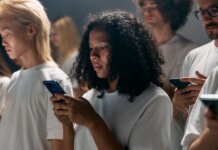 A diverse group of young adults focused on smartphones, symbolizing modern social connections and technology.