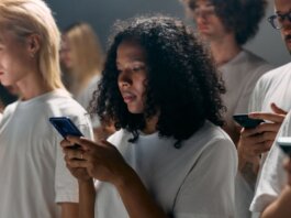 A diverse group of young adults focused on smartphones, symbolizing modern social connections and technology.