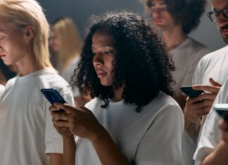 A diverse group of young adults focused on smartphones, symbolizing modern social connections and technology.
