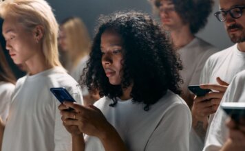 Meta передаст 15 тыс. AI-очков незрячим жителям Ирландии A diverse group of young adults focused on smartphones, symbolizing modern social connections and technology.