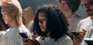 A diverse group of young adults focused on smartphones, symbolizing modern social connections and technology.