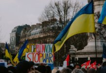 Канада выпустила заявление ко Дню независимости Украины A dynamic crowd in Paris rallies with Ukrainian flags and anti-war signs, advocating peace.