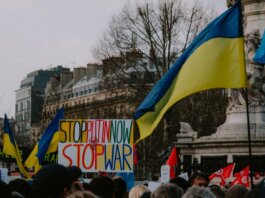 A dynamic crowd in Paris rallies with Ukrainian flags and anti-war signs, advocating peace.