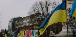 A dynamic crowd in Paris rallies with Ukrainian flags and anti-war signs, advocating peace.