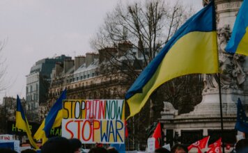 A dynamic crowd in Paris rallies with Ukrainian flags and anti-war signs, advocating peace.