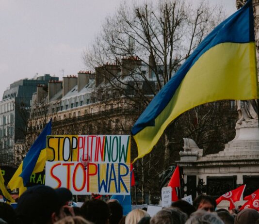 A dynamic crowd in Paris rallies with Ukrainian flags and anti-war signs, advocating peace.