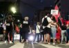 A group of people gathered during a nighttime feminist protest on a city street.