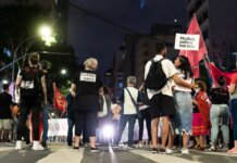 A group of people gathered during a nighttime feminist protest on a city street.
