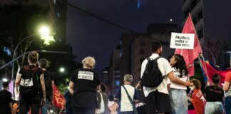 Консерваторы и «Блок Квебекуа» требуют расследования дела о шпионаже A group of people gathered during a nighttime feminist protest on a city street.