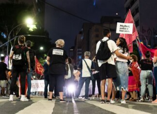 A group of people gathered during a nighttime feminist protest on a city street.