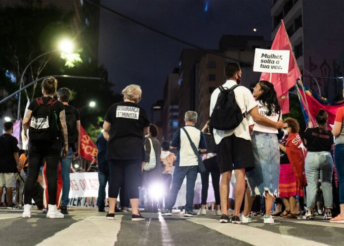 A group of people gathered during a nighttime feminist protest on a city street.