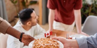A group of people sharing a pie with a Canadian flag, symbolizing unity and celebration.