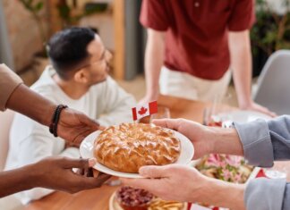 Пьер Пуальевр требует от Карни «хорошей сделки» с США A group of people sharing a pie with a Canadian flag, symbolizing unity and celebration.