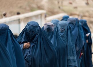 Канада отмечает пять лет с момента захвата Афганистана талибами A group of women covered in blue burqas walking outdoors in Afghanistan, highlighting cultural attire.