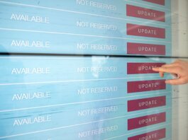 A hand interacts with a digital touchscreen interface showing availability and update options.