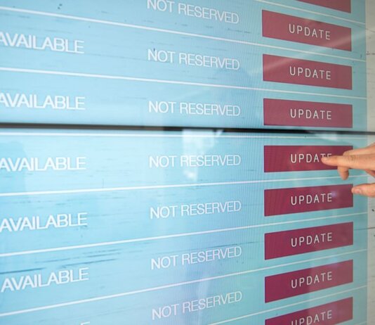 A hand interacts with a digital touchscreen interface showing availability and update options.