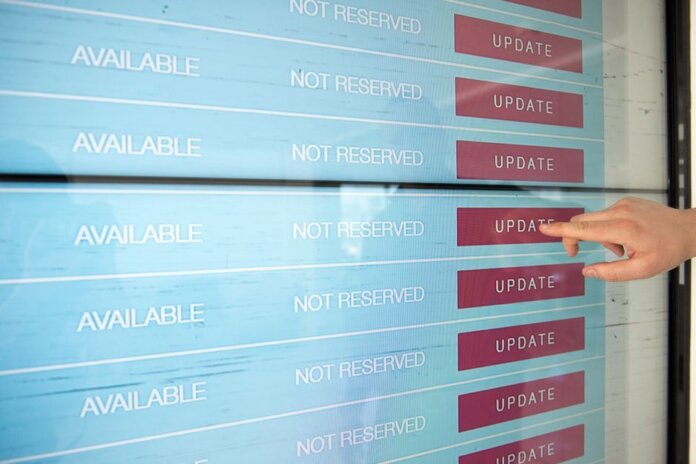 A hand interacts with a digital touchscreen interface showing availability and update options. A hand interacts with a digital touchscreen interface showing availability and update options.