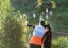 Канада отметила Всемирный день гуманитарной помощи A humanitarian worker wearing a World Vision vest assists a child in a lush, sunny environment.