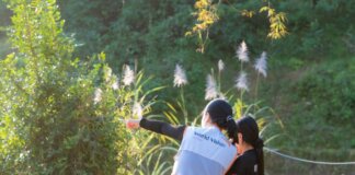 Канада отметила Всемирный день гуманитарной помощи A humanitarian worker wearing a World Vision vest assists a child in a lush, sunny environment.