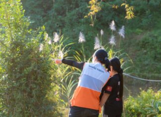 Канада отметила Всемирный день гуманитарной помощи A humanitarian worker wearing a World Vision vest assists a child in a lush, sunny environment.