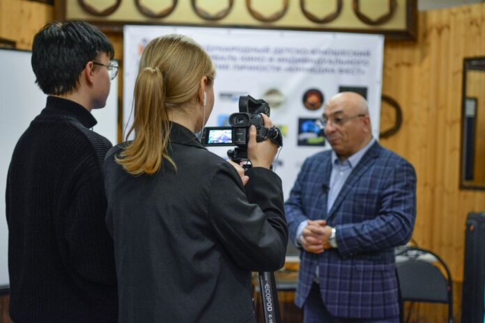 A journalist records an interview with a man using a camcorder indoors. A journalist records an interview with a man using a camcorder indoors.