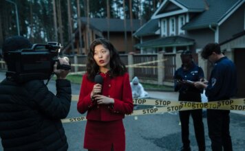 A journalist reporting from a crime scene with police officers and cameraman.