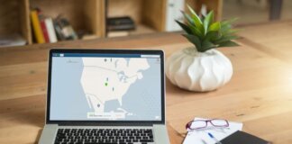 A laptop displaying VPN software sits on a wooden desk with a notepad and plant offering a secure workspace vibe.