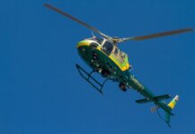 A Los Angeles County Sheriff helicopter soars through a clear blue sky.