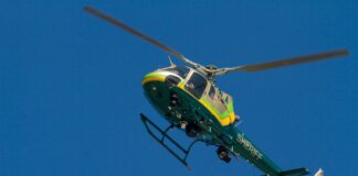 A Los Angeles County Sheriff helicopter soars through a clear blue sky.
