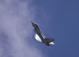 A military jet soaring through a clear blue sky, showcasing flight capabilities.