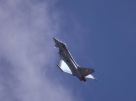 A military jet soaring through a clear blue sky, showcasing flight capabilities.