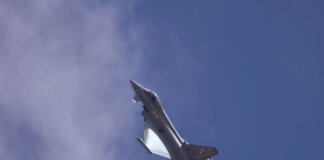 A military jet soaring through a clear blue sky, showcasing flight capabilities.