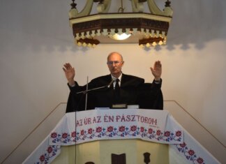 A pastor delivers a sermon inside a church in Vásárosnamény, offering blessings from the pulpit.