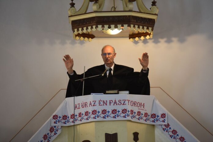 A pastor delivers a sermon inside a church in Vásárosnamény, offering blessings from the pulpit. A pastor delivers a sermon inside a church in Vásárosnamény, offering blessings from the pulpit.