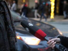 A person being interviewed on a Vancouver street, holding a microphone.
