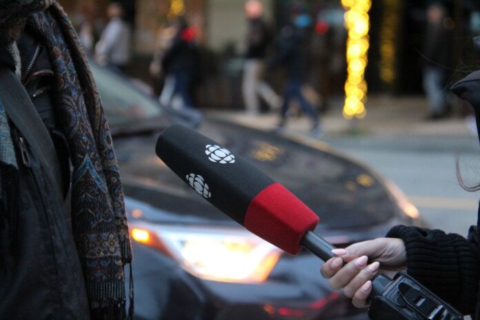 A person being interviewed on a Vancouver street, holding a microphone.