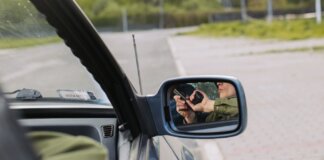 A person with a gun captured in the car's side mirror, suggesting a mysterious scenario.