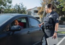 A police officer interacts with a driver during a daytime traffic stop on a residential street.