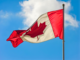 A vibrant Canadian flag waving against a blue sky with clouds.