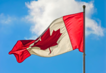 Правительство Канады поддержит Карибский карнавал в Торонто A vibrant Canadian flag waving against a blue sky with clouds.