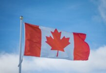 A vibrant Canadian flag waving in the breeze against a bright blue sky, symbolizing national pride.