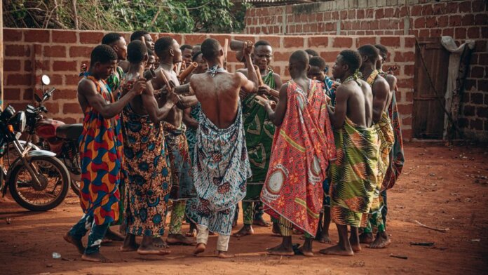 A vibrant cultural ceremony in Benin featuring a group in traditional clothing engaging in a ritual dance. A vibrant cultural ceremony in Benin featuring a group in traditional clothing engaging in a ritual dance.
