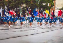 A vibrant marching band parades through the streets of Victoria, BC, showcasing flags and uniforms.