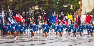 A vibrant marching band parades through the streets of Victoria, BC, showcasing flags and uniforms.