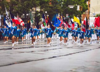 Проекты поддержки франкоязычных общин в Канаде A vibrant marching band parades through the streets of Victoria, BC, showcasing flags and uniforms.